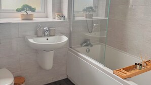 Une salle de bain moderne avec une douche à parois de verre, un lavabo blanc et des toilettes.