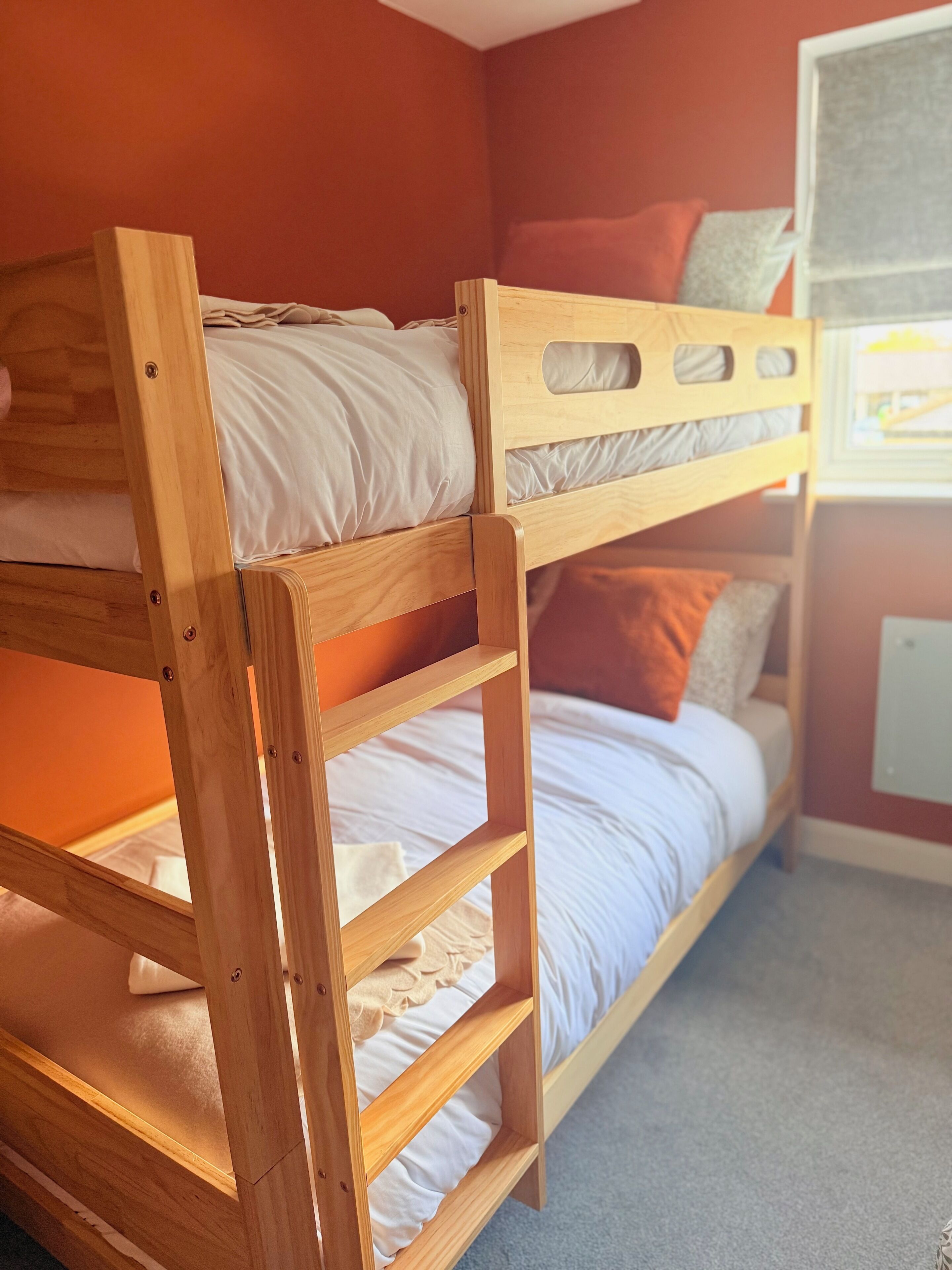A bunk bed with a wooden frame and white bedding.