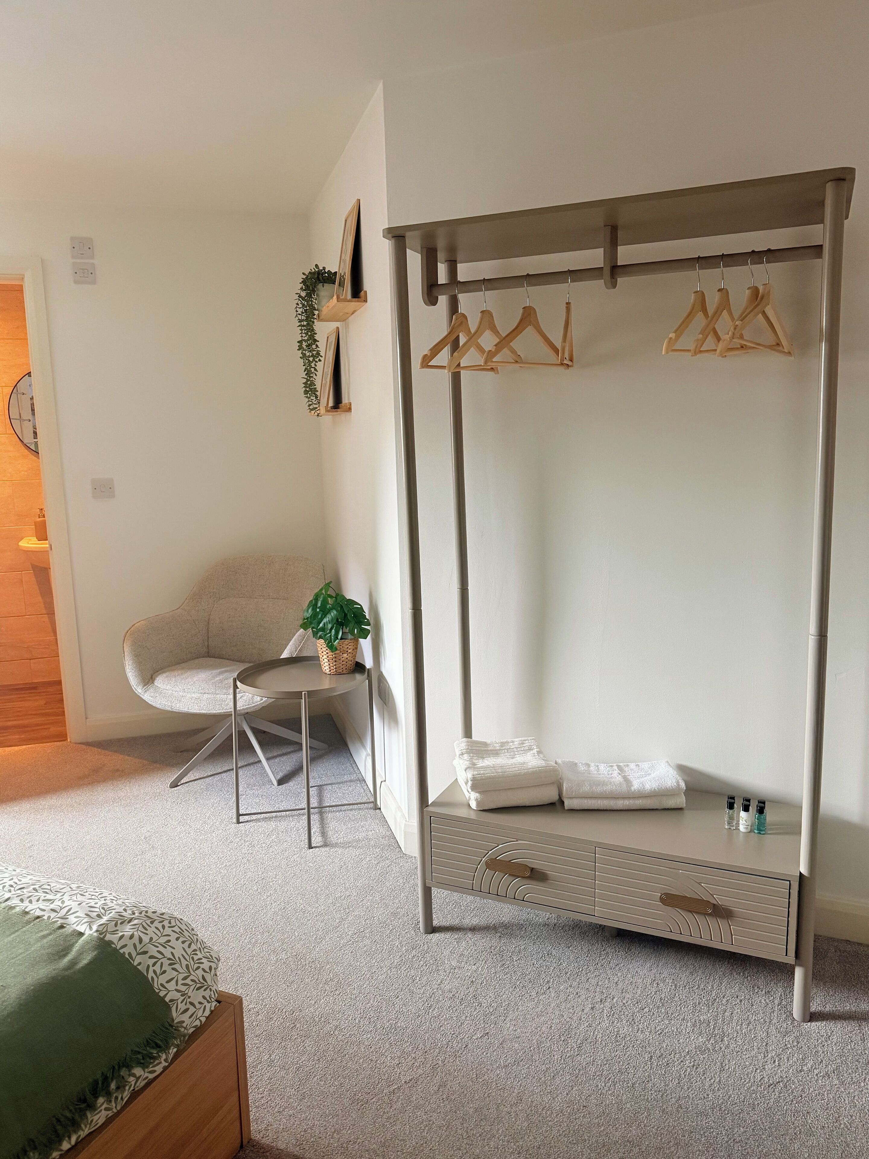 Une chambre à coucher comprenant un lit, une table de chevet, un portant à vêtements et une chaise.