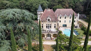 Un edificio grande con piscina, rodeado de árboles y un jardín.