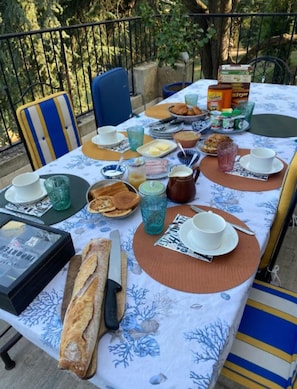 Mesa al aire libre con diversos alimentos, platos y cubiertos.