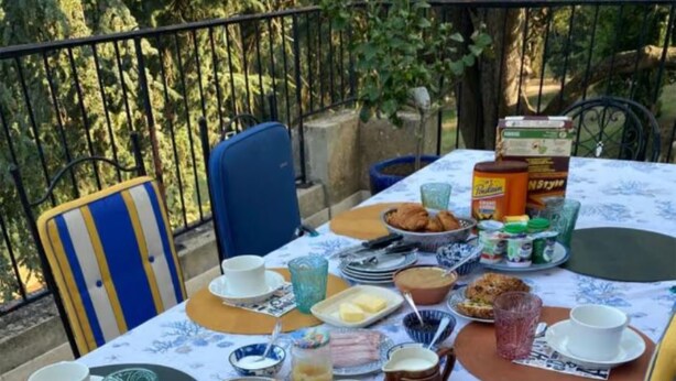 An outdoor dining table with various food items, plates, and cutlery.