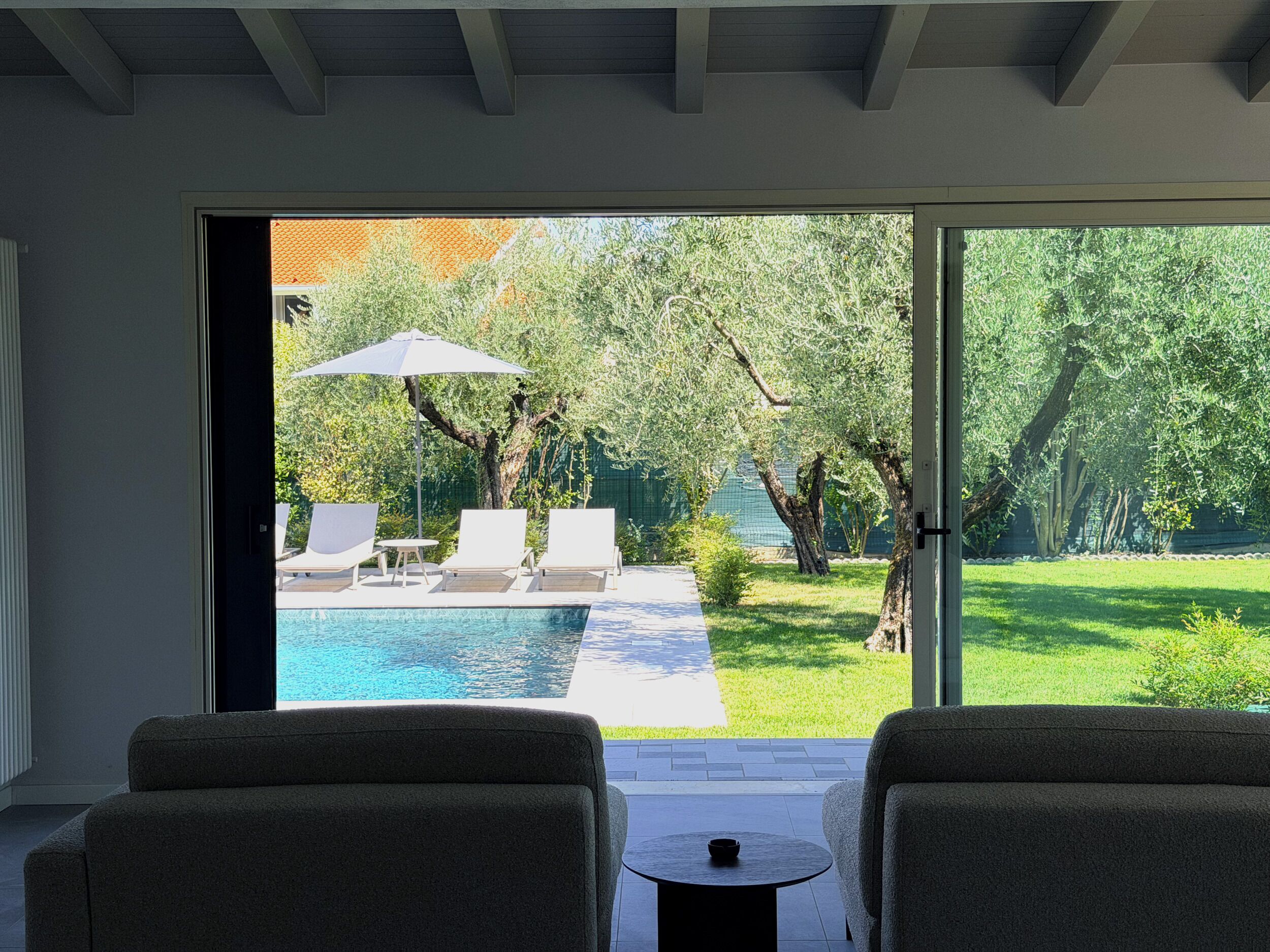 Une chambre avec vue sur une piscine extérieure, deux chaises longues et une petite table.