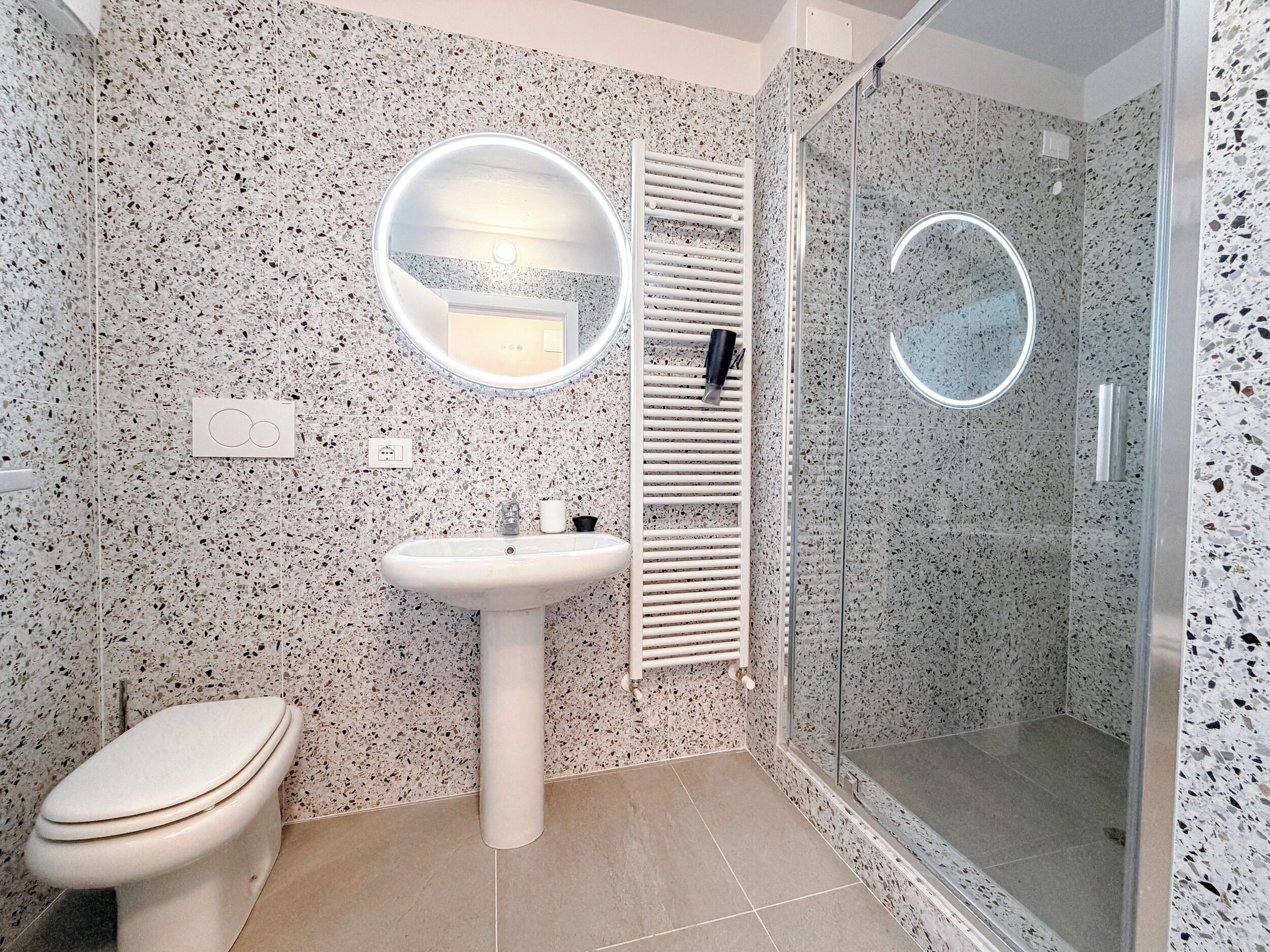 A bathroom with a white sink, toilet, and a glass-enclosed shower area.