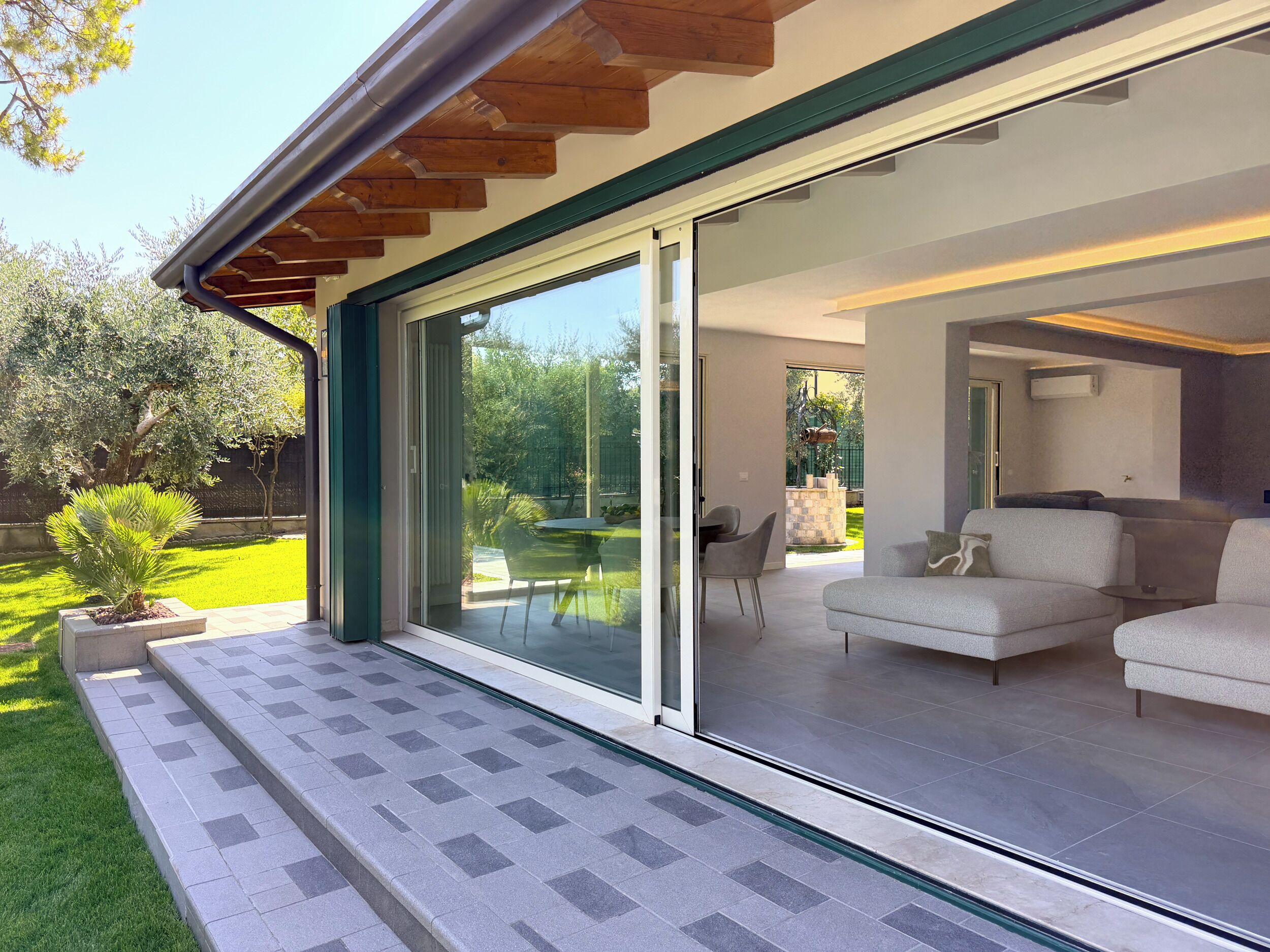 A modern house with a sliding glass door leading to a patio area.