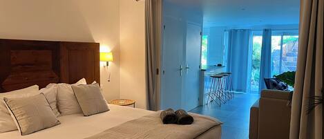 Une chambre d’hôtel comprenant un lit, une table de chevet, une lampe, une vue sur l’espace extérieur et un coin repas.