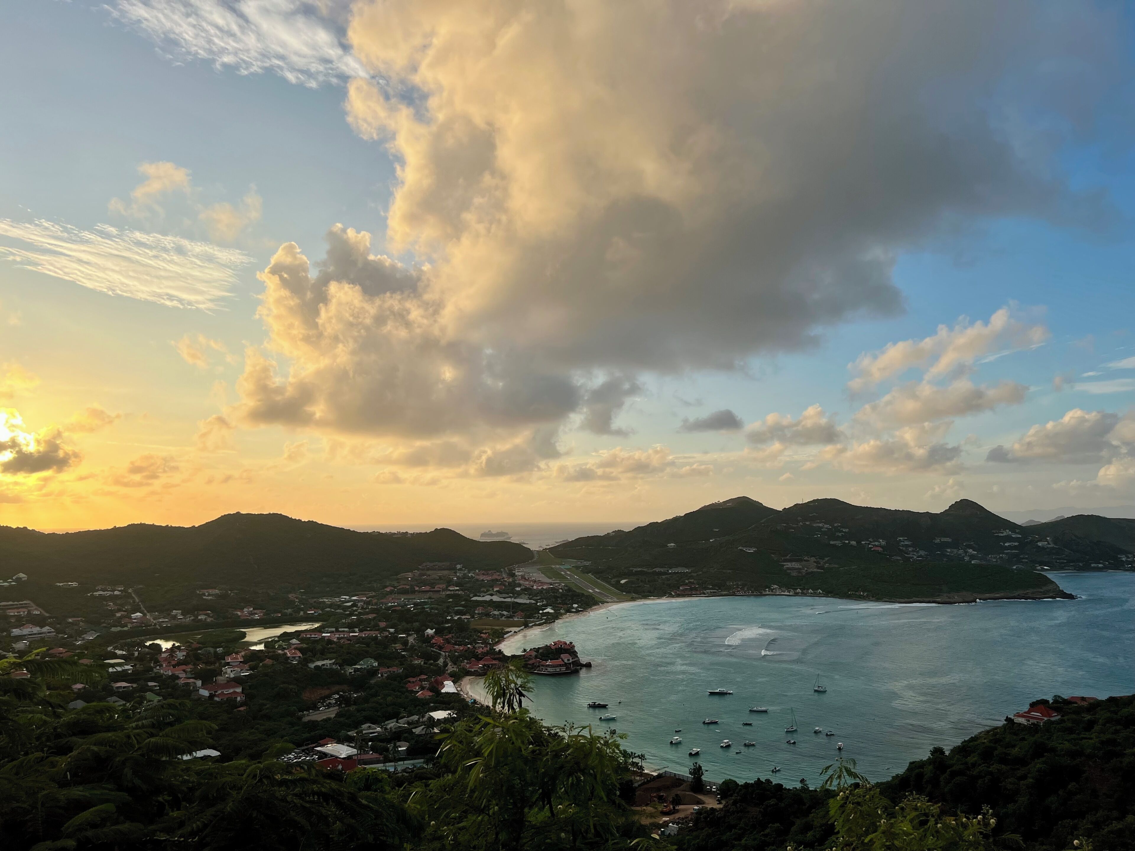 A coastal town with a view of the sea, boats, and distant mountains.
