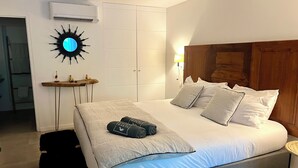 Ein Schlafzimmer mit Bett, Nachttisch, Wandaircondition und einer außergewöhnlichen Wanddekoration.