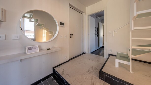 A modern interior with a circular mirror, a staircase, and a small table. - LUX APARTMENT - Comfort and Style in the Heart of Santa Margherita (Santa Margherita Ligure)