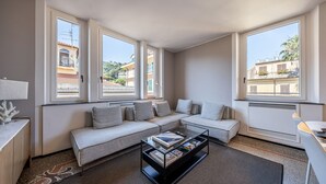 A modern living room with a sofa, a coffee table, and large windows. - LUX APARTMENT - Comfort and Style in the Heart of Santa Margherita (Santa Margherita Ligure)