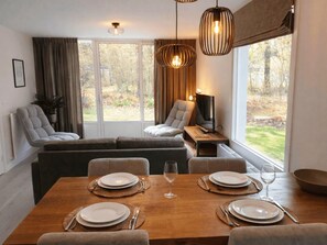 Ein Essbereich mit einem Holztisch, gedeckt für vier Personen, einer Couch und einem Fernseher auf einem Schrank.