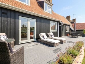 Ein modernes Haus mit einer Terrasse, ausgestattet mit zwei Liegestühlen und einem Tisch.