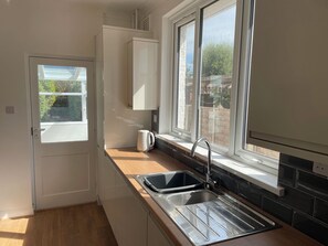 A small kitchen with a window, a sink, and a kettle. - Summer Cottage (Littlehampton)