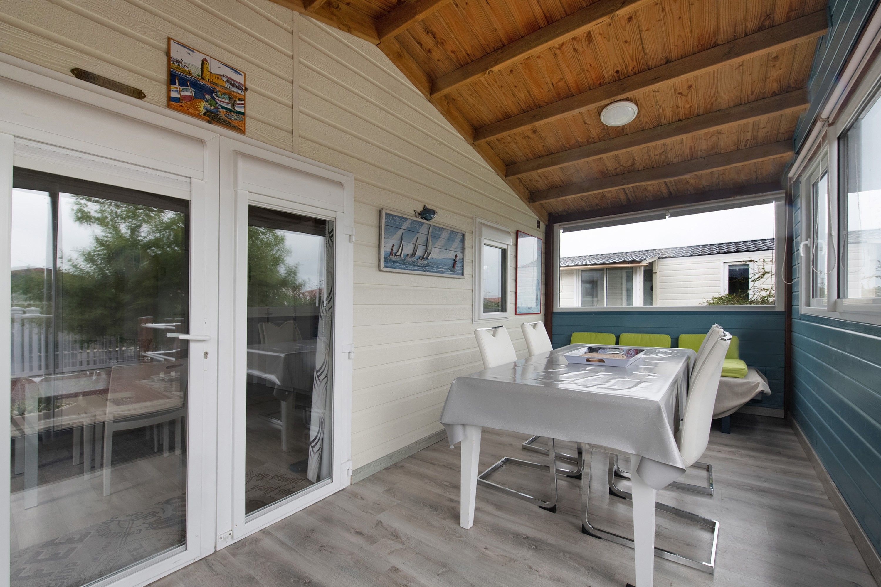 A covered patio with a table and chairs, wooden ceiling beams, and a view of the outside.