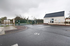 A gated entrance to a building with a flat roof and a signboard.