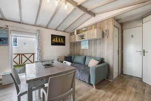 A cozy room with a dining table, chairs, a sofa, and a wooden floor.