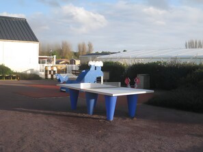 A blue and white outdoor table with a white top, surrounded by blue legs, set on a gravel surface.