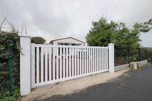 Een omheind landgoed met een witte hek, een oprit en een huis op de achtergrond.