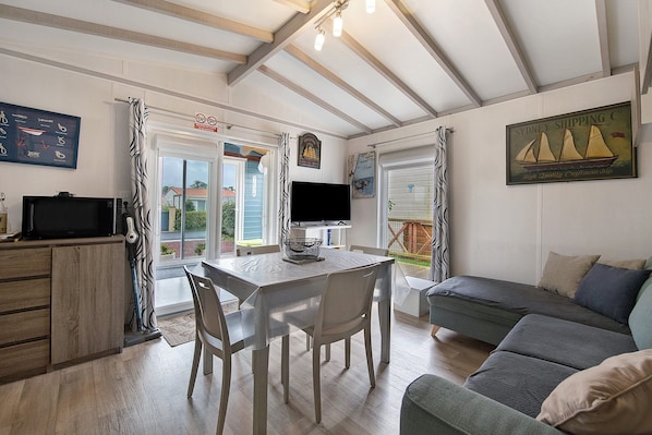 A cozy interior with a dining area, a sofa, and a television.