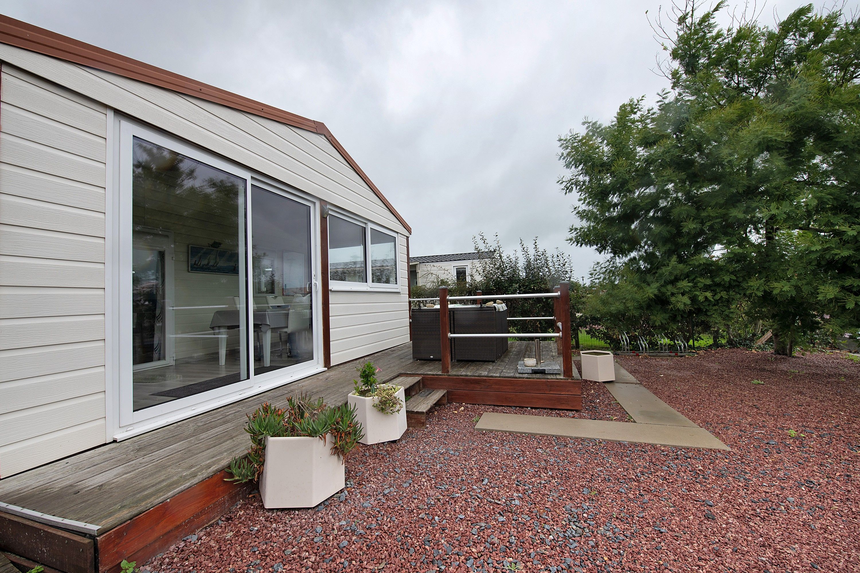 En boligejendom med en overdækket terrasse, træterrasse og grusbelagt indkørsel.