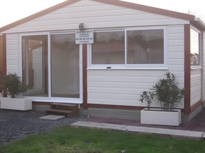A single-story building with a large sliding glass door entrance, a small porch, and a sign indicating a location number.
