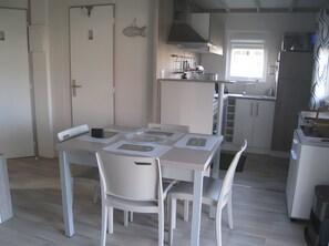 A modern kitchen with white cabinetry, a dining table with chairs, and a window providing natural light.