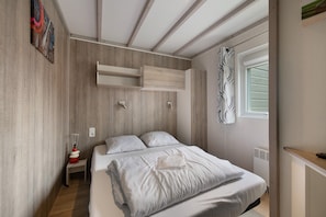 A bedroom with a bed, bedside tables, a window, and a built-in wardrobe.