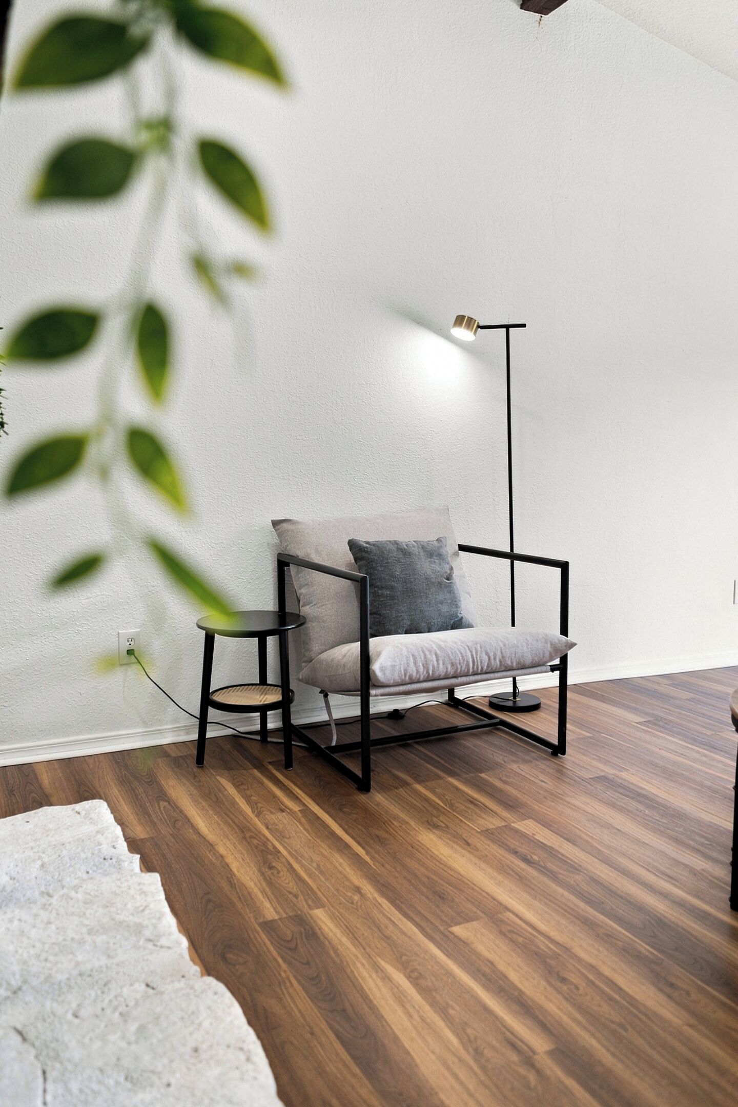 Ein moderner Stuhl mit Kissen, eine Stehlampe und ein Holzboden.