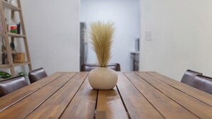 Un tavolo da pranzo in legno con un vaso di erba secca al centro.