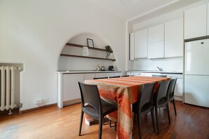 A modern kitchen with white cabinets, a built-in oven, and a dining area with a striped tablecloth and chairs. - Spacious 200 sqm apartment, ideal for groups of up to 8 people, located on the 2nd floor of a building with an elevator.The property is centrally located, just a 7-minute walk from the San Babila M1 metro stop and a 14-minute walk from the Duomo.Essent (Milan)