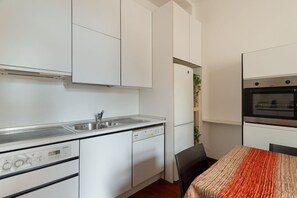 A compact kitchen with a dishwasher, oven, and a small dining area with a table and chairs. - Spacious 200 sqm apartment, ideal for groups of up to 8 people, located on the 2nd floor of a building with an elevator.The property is centrally located, just a 7-minute walk from the San Babila M1 metro stop and a 14-minute walk from the Duomo.Essent (Milan)
