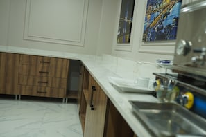 A kitchen with white countertops, wooden cabinets, and a stainless steel sink. - ÇELİK PALACE HOTEL (İstanbul)