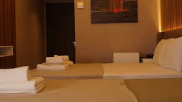 Habitación de hotel con dos camas, un cuadro de un paisaje urbano y una puerta que da a otra habitación.