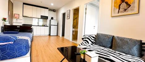 Um espaço de estar moderno com sofá, mesa de centro e cama com colcha estampada.