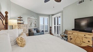 Ein Schlafzimmer mit einem großen Bett, einem Fernseher, einer Kommode und einem Deckenventilator.