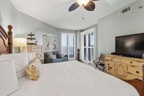Een slaapkamer met een groot bed, een televisie, een dressoir en een plafondventilator.