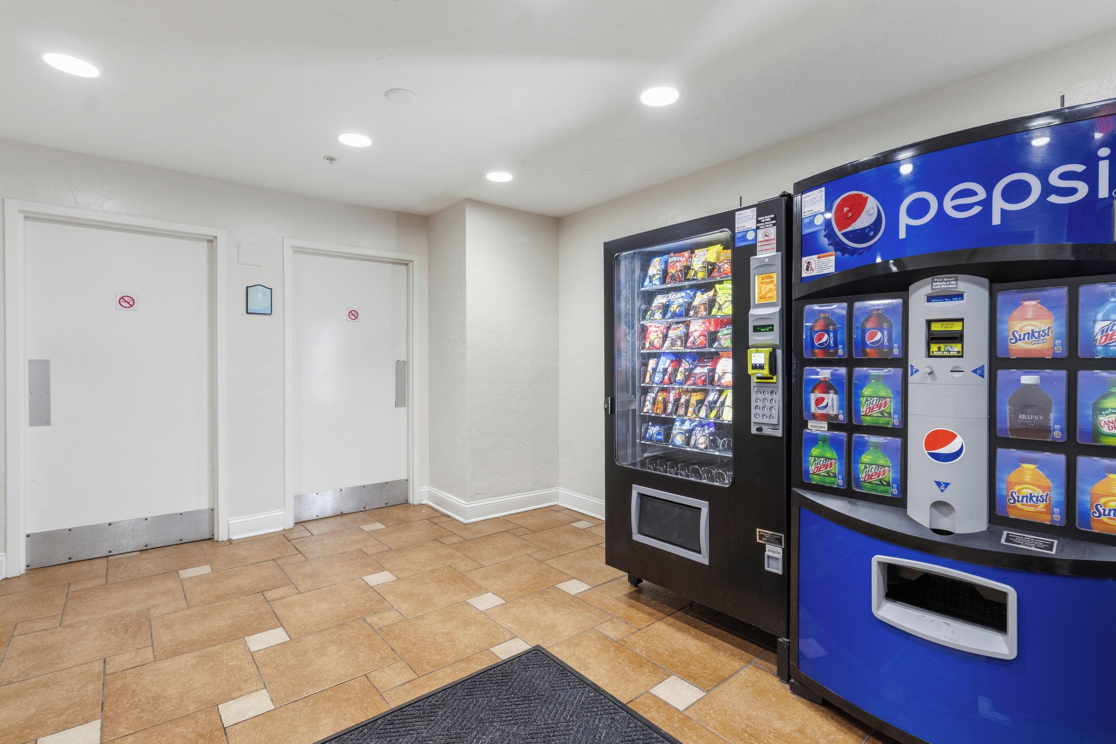 A vending machine area with Pepsi and Mountain Dew options, a no-smoking sign, and a men's restroom.