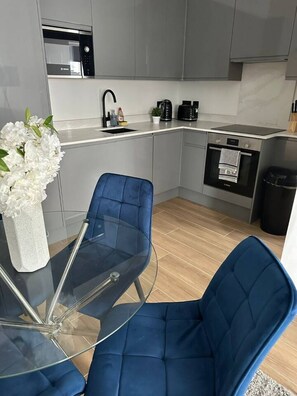 A modern kitchen with grey cabinets, a Bosch microwave, and a coffee maker. - Modern 2BR Flat | North Finchley (Greater London)