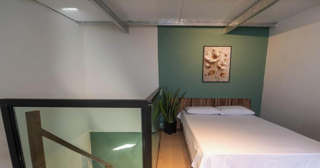 Ein Schlafzimmer mit einem Bett, einer grünen Wand und einem gerahmten Bild.