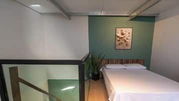 Ein Schlafzimmer mit einem Bett, einer grünen Wand und einem gerahmten Bild.