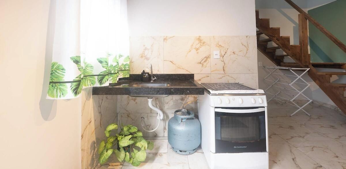 Une cuisine compacte équipée d’un évier, d’une cuisinière et d’une bouteille de gaz.