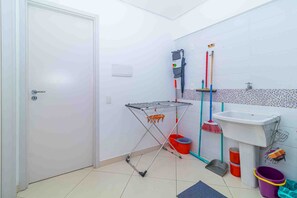 A small bathroom with a white sink, a mirror, a towel rack, a shower area, and a door. - Apto c Churrasqueira a 350m do Metr Campo Elisios (São Paulo)