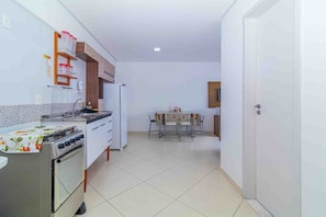 A compact kitchen with a stove, refrigerator, and a dining table with chairs. - Apto c Churrasqueira a 350m do Metr Campo Elisios (São Paulo)