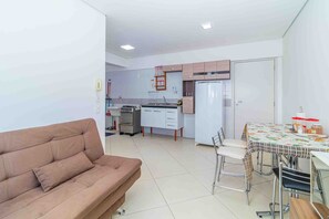 A compact living space with a kitchenette, a sofa, a dining table with chairs, and a refrigerator. - Apto c Churrasqueira a 350m do Metr Campo Elisios (São Paulo)