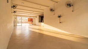 A hotel corridor with tiled floors, ceiling fans, and a view of the lobby area. - Apto c Churrasqueira a 350m do Metr Campo Elisios (São Paulo)