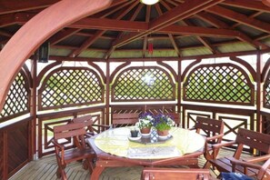 A wooden gazebo with a round table and chairs, surrounded by lattice panels. - Garden House on Sobieszewo Island (Gdańsk)