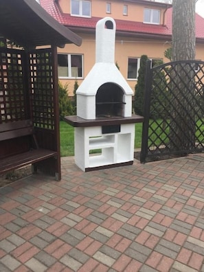Une terrasse extérieure en briques avec une structure de four d’extérieur blanche.