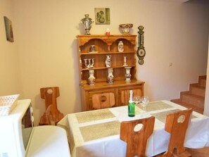 Ein Essbereich mit einem Holftisch als Buffet, Stühlen und einer Wanduhr.
