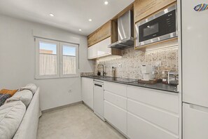 A modern kitchen with white cabinetry, a stainless steel microwave, and a built-in oven.