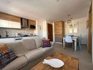A modern apartment with a kitchenette, a dining area, and a living room with a sofa and coffee table.